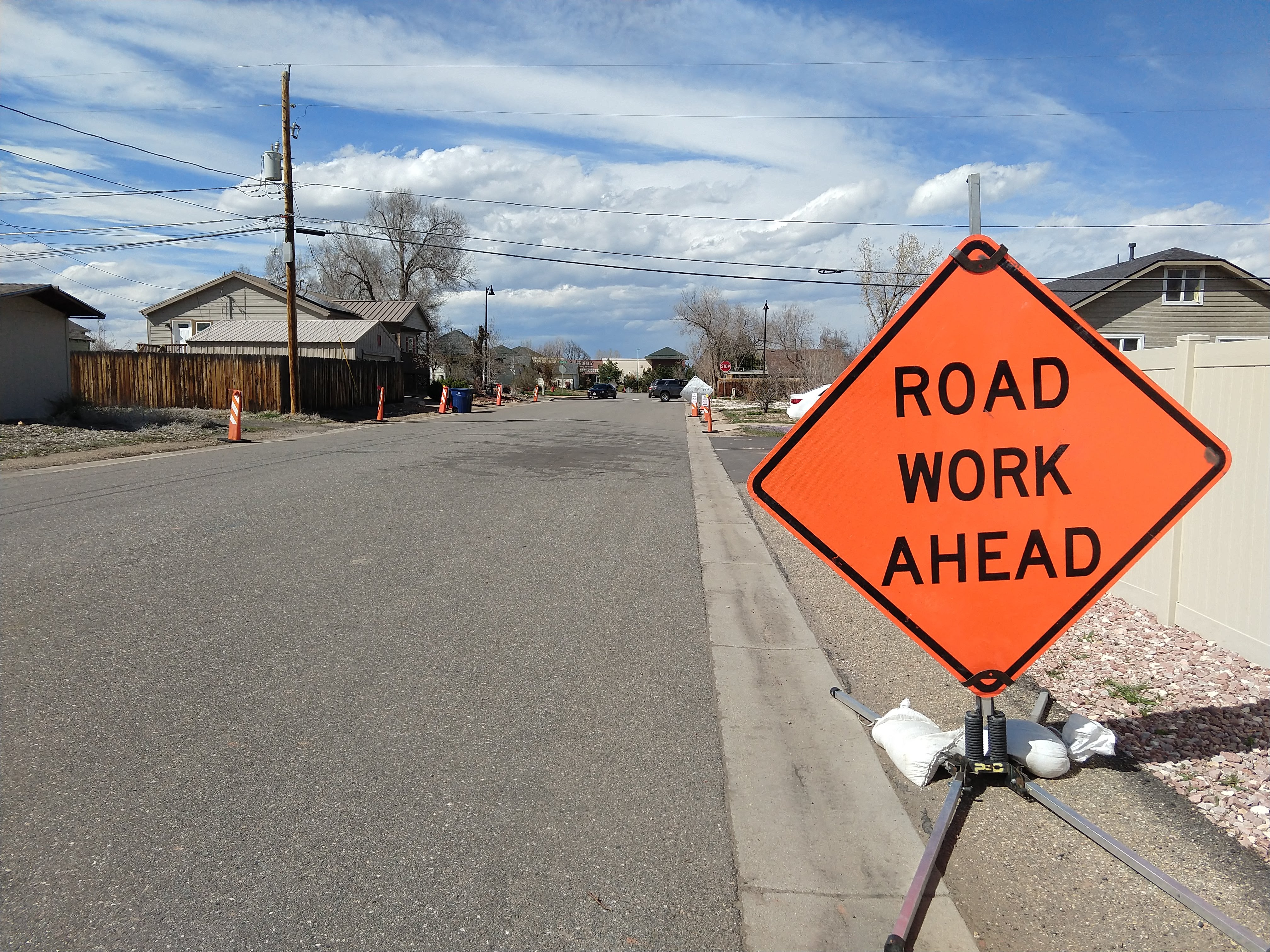 ROAD WORK AHEAD: an empty street with yellow cones on either side