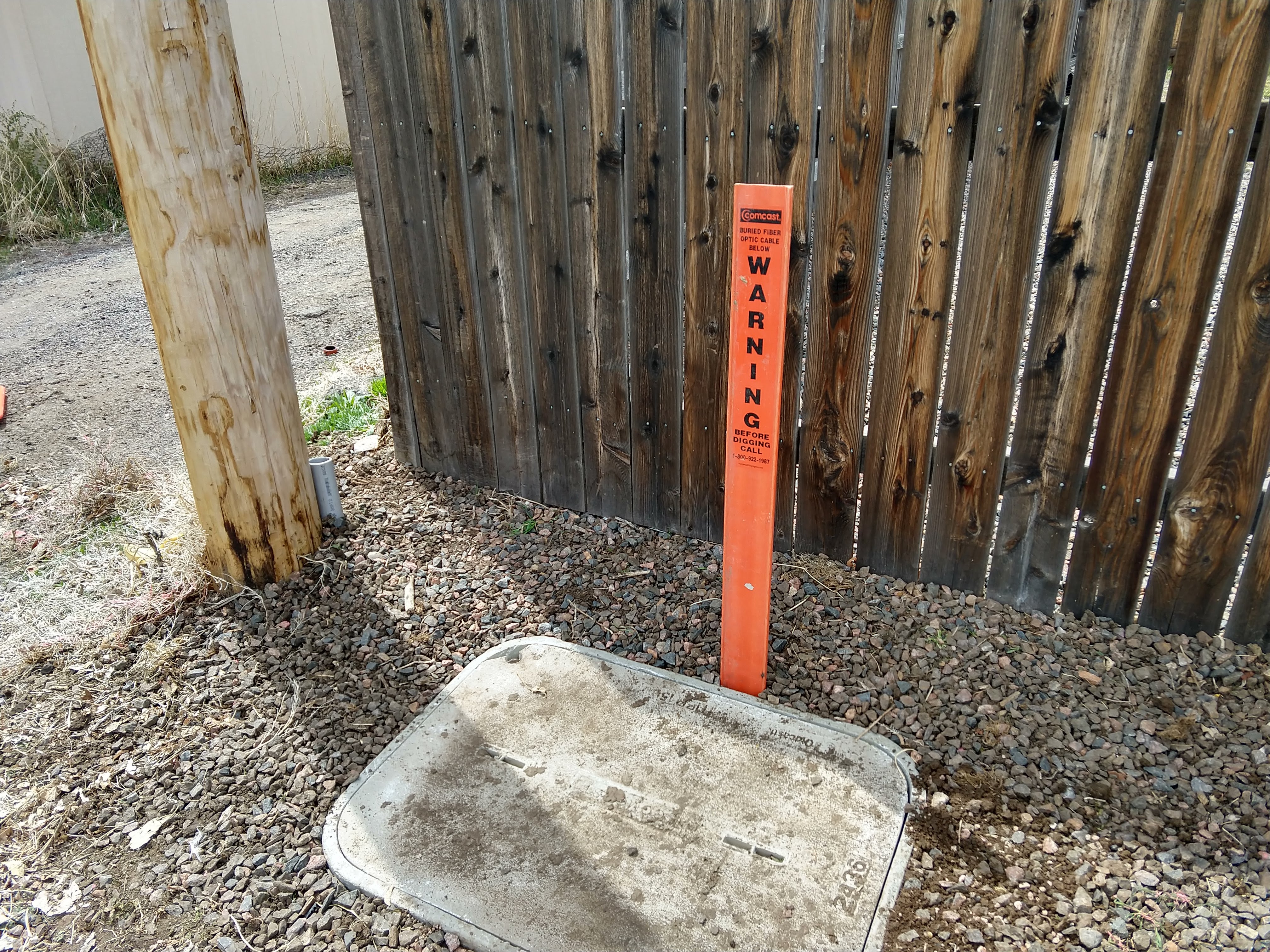 utility pole and in-ground box labeled with fiber warning